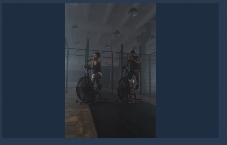 Two athletes on air bikes in a training facility